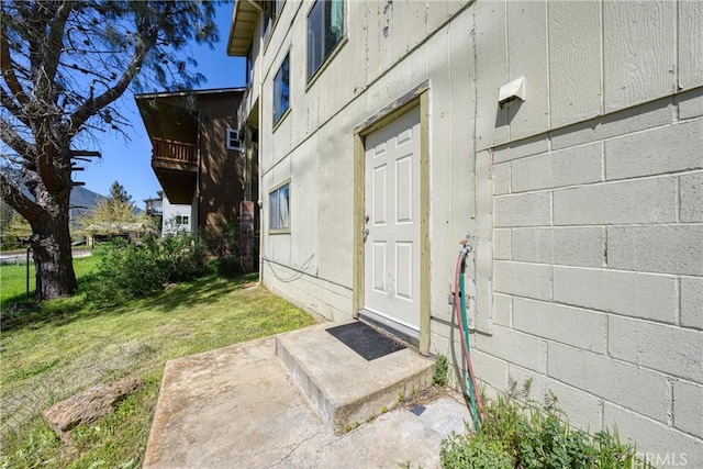 entrance to property with a yard and concrete block siding