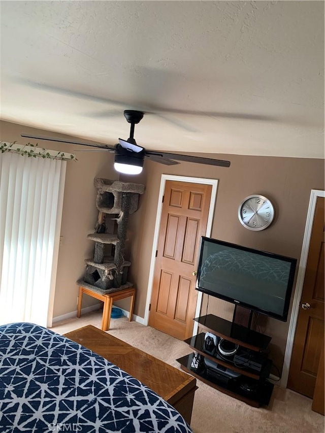 bedroom featuring a textured ceiling, light colored carpet, baseboards, and ceiling fan