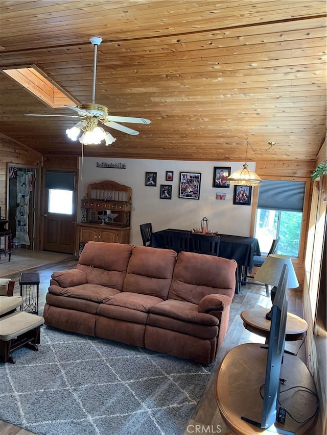 living room with lofted ceiling with skylight, ceiling fan, wood ceiling, and a healthy amount of sunlight