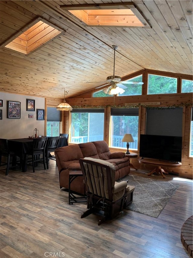 living area with vaulted ceiling with skylight, ceiling fan, wooden ceiling, and wood finished floors