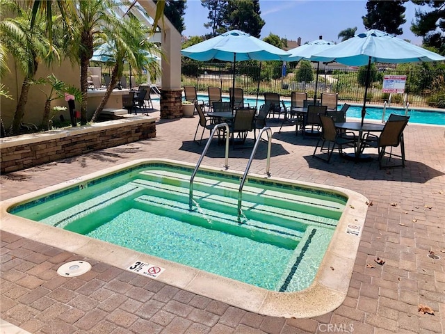 pool featuring fence, a community hot tub, and a patio area
