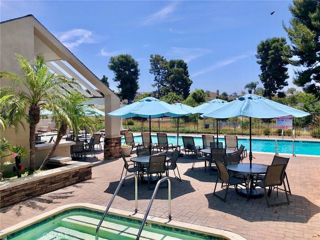 community pool featuring a community hot tub, a patio area, and fence