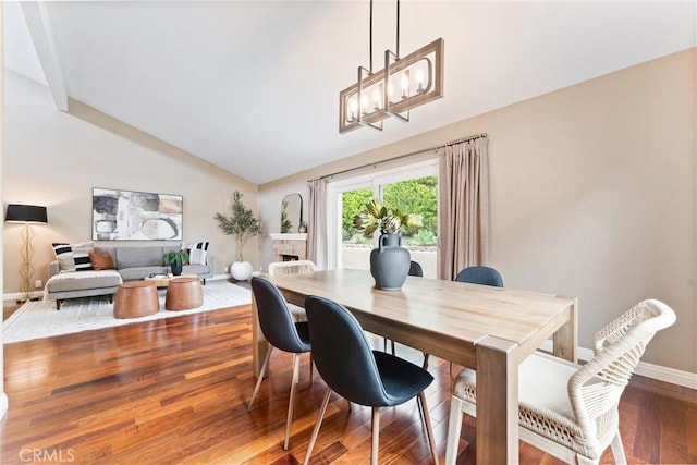 dining area with a notable chandelier, baseboards, vaulted ceiling, and wood finished floors