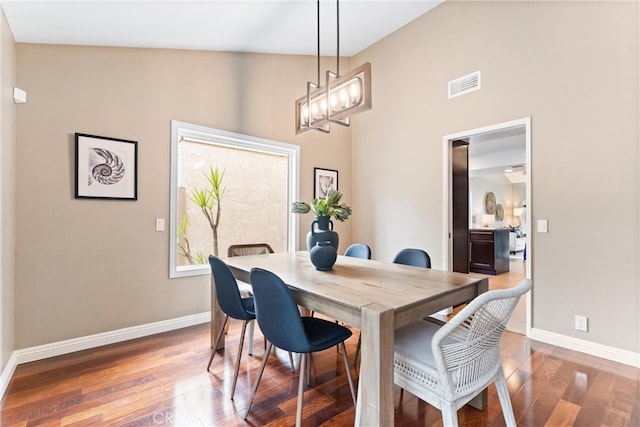 dining area featuring baseboards, visible vents, wood finished floors, and a high ceiling