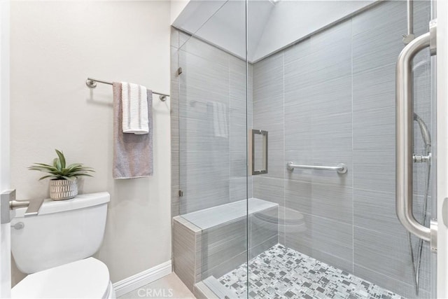 bathroom with baseboards, toilet, and a shower stall