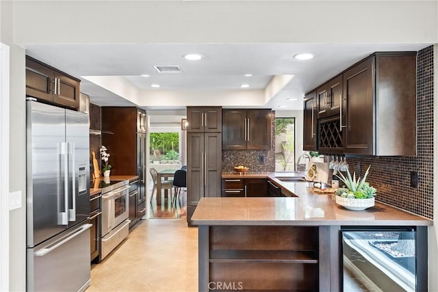 kitchen featuring stainless steel appliances, a sink, beverage cooler, and dark brown cabinets
