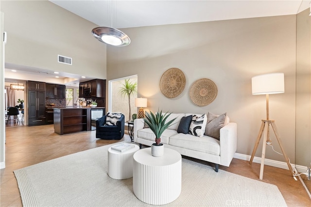 living area featuring light tile patterned floors, baseboards, and visible vents
