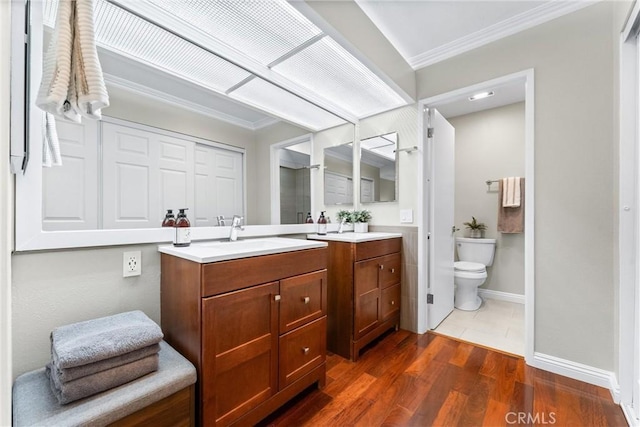 bathroom with vanity, toilet, baseboards, wood finished floors, and ornamental molding