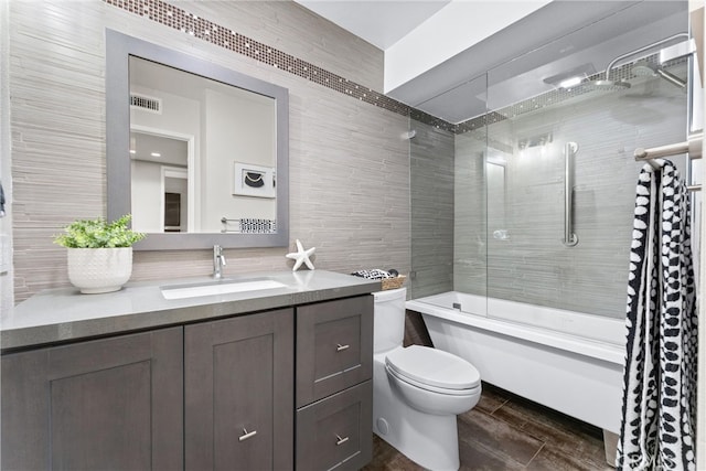 full bathroom featuring vanity, toilet, tile walls, bathing tub / shower combination, and visible vents