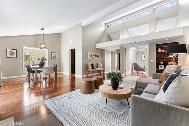 living room with baseboards, wood finished floors, and high vaulted ceiling