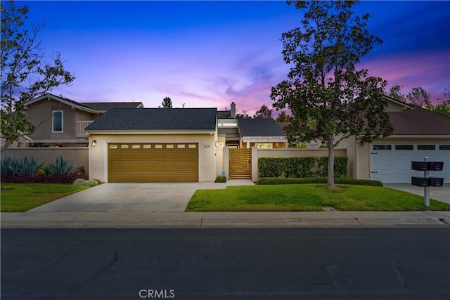 view of front of house with fence, a front yard, stucco siding, an attached garage, and driveway