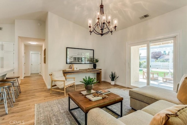 living area with light wood-style floors, a high ceiling, an inviting chandelier, and visible vents