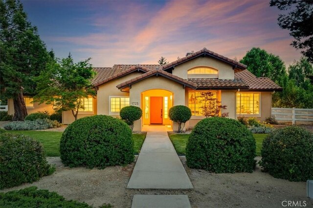 view of front of property featuring a tiled roof, fence, and stucco siding