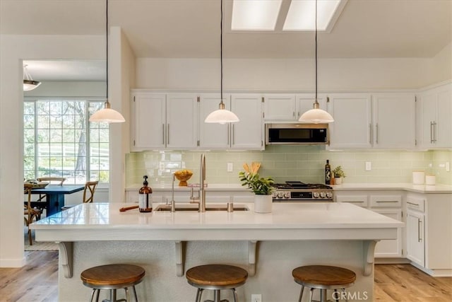 kitchen with appliances with stainless steel finishes, a sink, white cabinets, and a kitchen breakfast bar