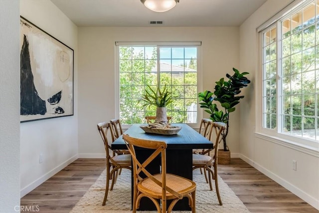 dining space featuring wood finished floors, baseboards, and visible vents