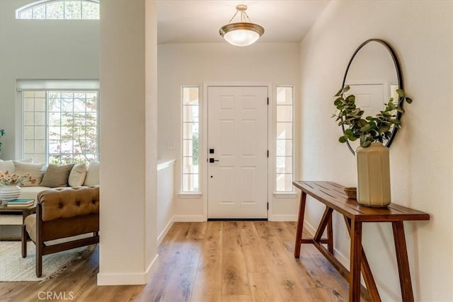 entryway featuring baseboards, light wood-style floors, and a healthy amount of sunlight