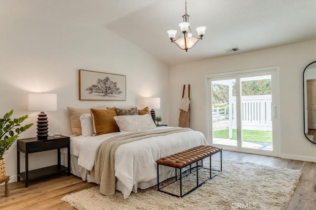 bedroom with light wood-style flooring, access to exterior, an inviting chandelier, and vaulted ceiling
