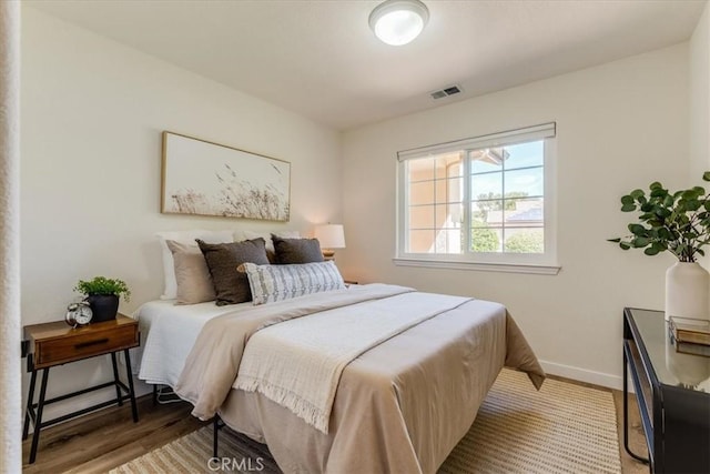 bedroom with visible vents, baseboards, and wood finished floors