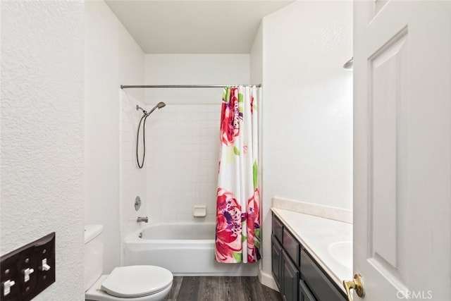 bathroom featuring toilet, a textured wall, shower / bath combo with shower curtain, vanity, and wood finished floors