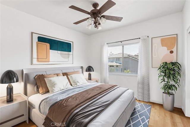 bedroom featuring light wood finished floors, baseboards, and a ceiling fan