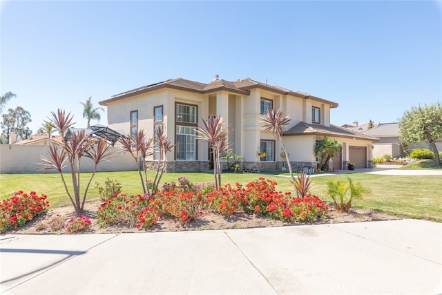 view of front of house with a front lawn, a garage, driveway, and stucco siding