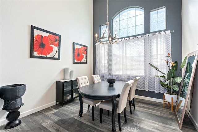 dining room featuring baseboards, a chandelier, a towering ceiling, and dark wood finished floors