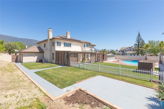 exterior space with a yard, a fenced backyard, stucco siding, solar panels, and a chimney