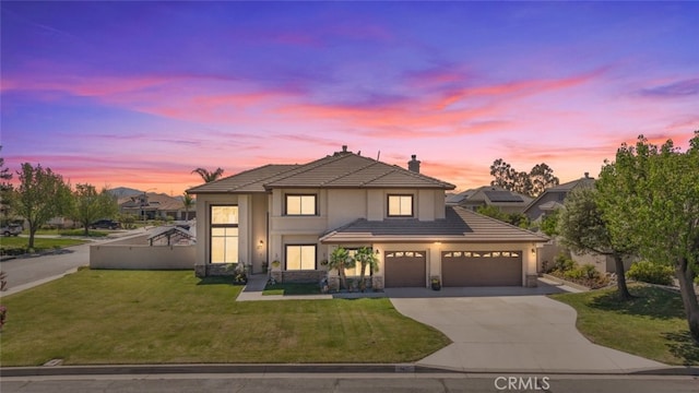 traditional home featuring a tiled roof, stucco siding, a front lawn, a chimney, and driveway