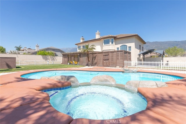 view of pool featuring a pool with connected hot tub, a fenced backyard, and a mountain view