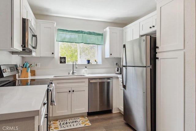 kitchen with stainless steel appliances, light countertops, white cabinets, and a sink