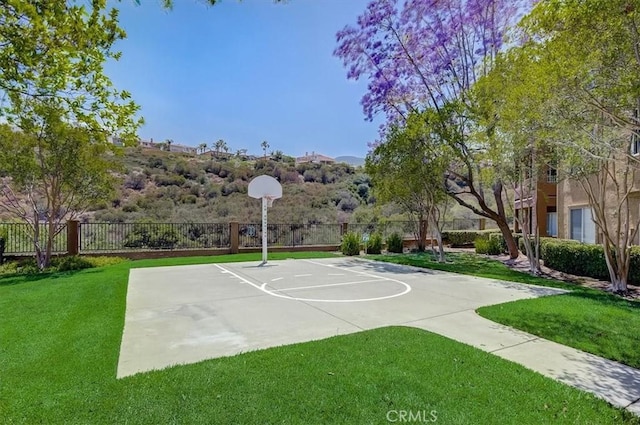 view of sport court featuring a lawn, community basketball court, and fence