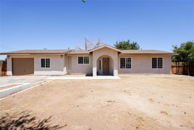 ranch-style house featuring a garage, stucco siding, and fence