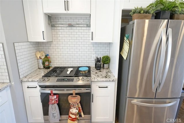 kitchen featuring white cabinets, tasteful backsplash, light stone counters, and appliances with stainless steel finishes