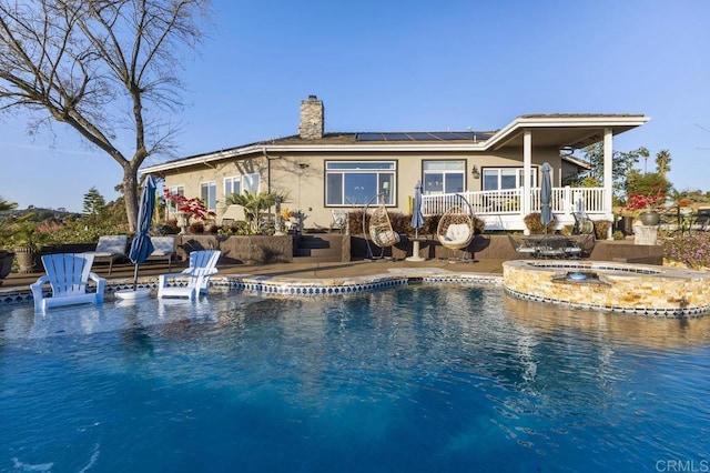 1078 Rainbow Crest Rd, Fallbrook, CA 92028 - back of house with stucco siding, roof mounted solar panels, a chimney, a patio, and a pool with connected hot tub