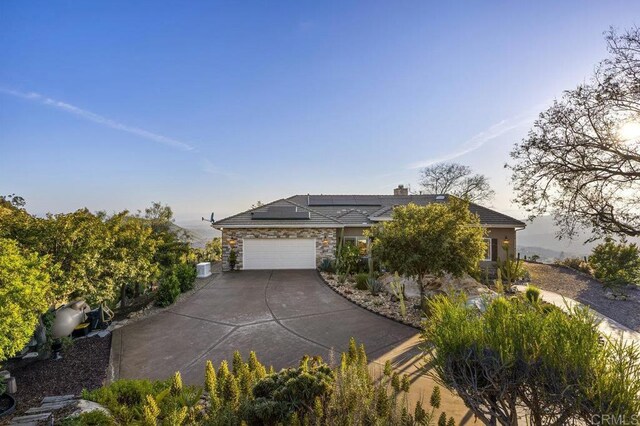 1078 Rainbow Crest Rd, Fallbrook, CA 92028 - view of front of house with stone siding, concrete driveway, solar panels, an attached garage, and a chimney