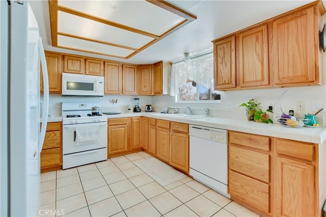 kitchen with a sink, light tile patterned floors, light countertops, and white appliances