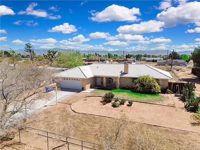 ranch-style house with a tiled roof, an attached garage, fence, and concrete driveway