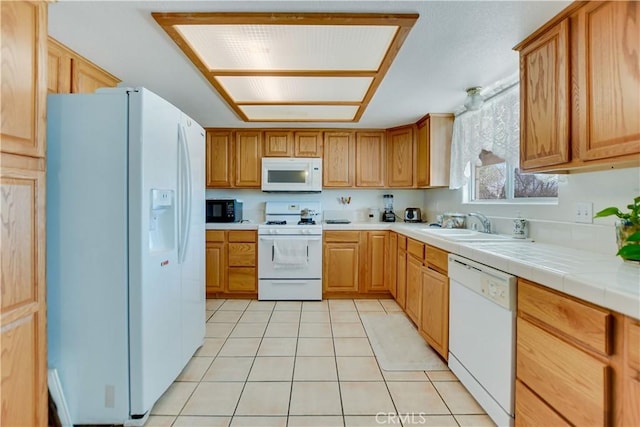 kitchen featuring a sink, light tile patterned floors, white appliances, and tile countertops