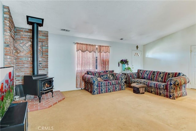 living area featuring a wood stove, carpet flooring, and visible vents