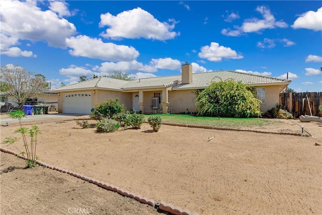 ranch-style home with concrete driveway, stucco siding, an attached garage, a tiled roof, and fence