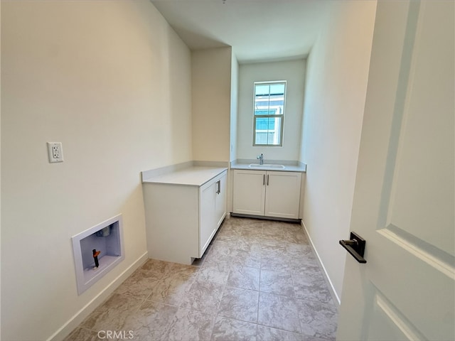 laundry area with baseboards, a sink, washer hookup, and cabinet space