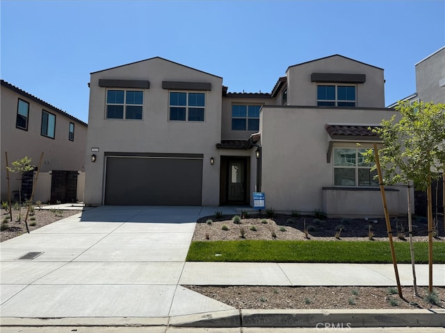 view of front of home featuring a garage, stucco siding, a tiled roof, and concrete driveway
