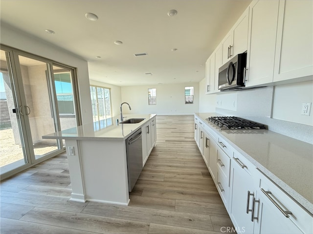 kitchen with light countertops, white cabinetry, light wood-style floors, appliances with stainless steel finishes, and a sink