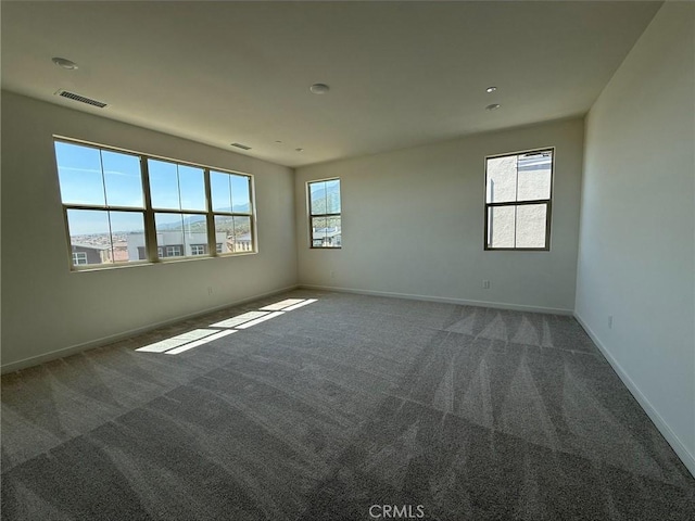 carpeted spare room featuring baseboards and visible vents