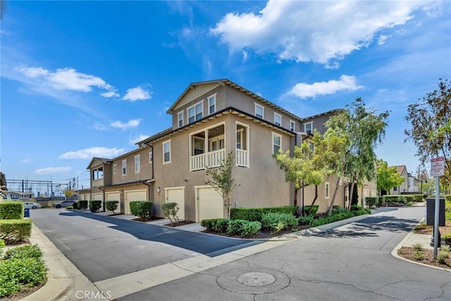 exterior space featuring stucco siding, an attached garage, driveway, and a residential view