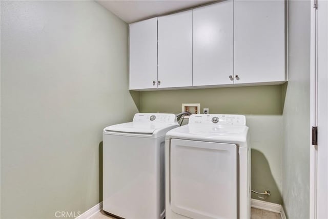 clothes washing area with baseboards, washer and dryer, and cabinet space