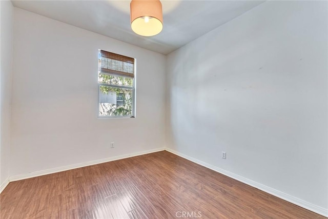 unfurnished room with baseboards and wood finished floors