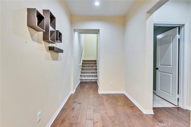 hallway featuring wood-type flooring, stairs, and baseboards