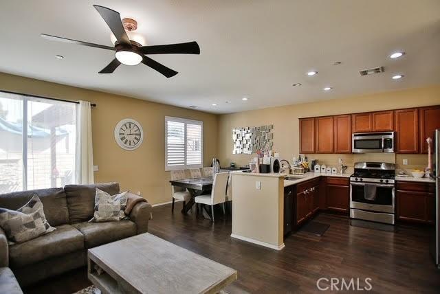 kitchen featuring visible vents, open floor plan, dark wood-style floors, light countertops, and appliances with stainless steel finishes