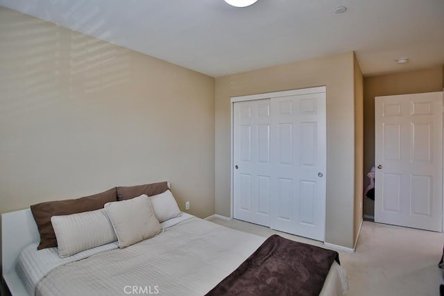 bedroom with baseboards, light carpet, and a closet